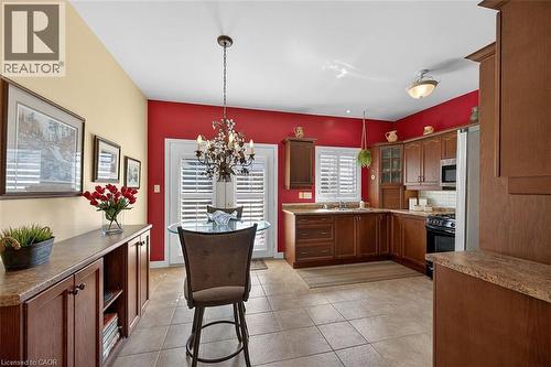 Kitchen featuring a chandelier, stainless steel appliances, glass insert cabinets, decorative backsplash, and light tile patterned floors - 48 Hallmark Trail, Hamilton, ON - Indoor