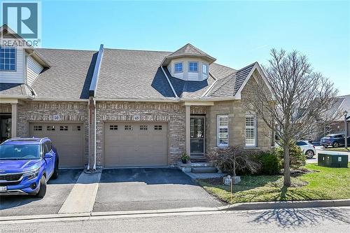 View of front of home with driveway, a shingled roof, stone siding, an attached garage, and brick siding - 48 Hallmark Trail, Hamilton, ON - Outdoor