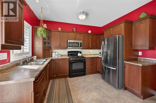 Kitchen featuring glass fronted cabinets, stainless steel appliances, tasteful backsplash, hanging light fixtures, and wood finish cabinets - 48 Hallmark Trail, Hamilton, ON - Indoor Photo Showing Kitchen With Double Sink