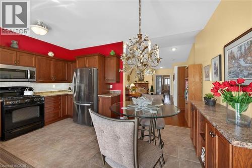 Kitchen with stainless steel appliances, light stone counters, a chandelier, backsplash, and light tile patterned floors - 48 Hallmark Trail, Hamilton, ON - Indoor Photo Showing Kitchen