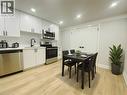 Kitchen with stainless steel appliances, backsplash, light countertops, white cabinets, and light wood-style floors - 588 Barton Street E Unit# 10, Hamilton, ON  - Indoor 