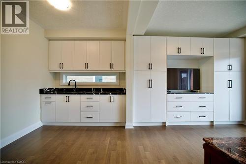 Kitchen with a textured ceiling, white cabinetry, and dark wood-style flooring - 559 Balsam Poplar Street, Waterloo, ON - Indoor Photo Showing Kitchen