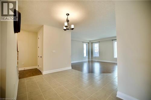 Empty room with a chandelier, a textured ceiling, and light tile patterned floors - 559 Balsam Poplar Street, Waterloo, ON - Indoor Photo Showing Other Room
