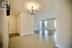 Empty room with a chandelier, a textured ceiling, and light tile patterned floors - 
