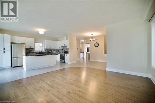 Unfurnished living room featuring light wood-style flooring and a chandelier - 559 Balsam Poplar Street, Waterloo, ON - Indoor Photo Showing Kitchen