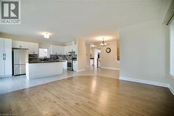 Unfurnished living room featuring light wood-style flooring and a chandelier - 