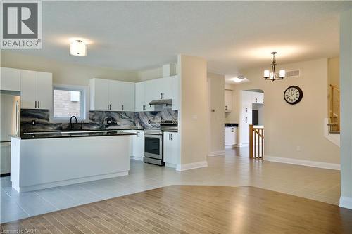 Kitchen with dark countertops, white cabinetry, stainless steel appliances, and light tile patterned floors - 559 Balsam Poplar Street, Waterloo, ON - Indoor Photo Showing Kitchen