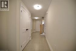 Hall featuring a textured ceiling and light tile patterned floors - 