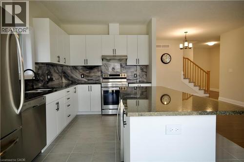 Kitchen with stainless steel appliances, white cabinetry, and dark stone countertops - 559 Balsam Poplar Street, Waterloo, ON - Indoor Photo Showing Kitchen