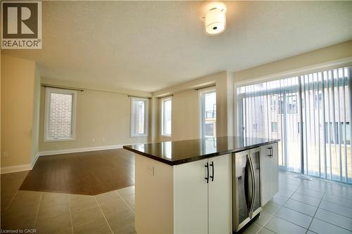 Kitchen featuring beverage cooler, a center island, white cabinets, open floor plan, and light tile patterned flooring - 559 Balsam Poplar Street, Waterloo, ON - Indoor Photo Showing Other Room