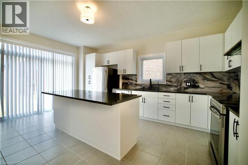 Kitchen with a center island, electric range, tasteful backsplash, white cabinetry, and a textured ceiling - 559 Balsam Poplar Street, Waterloo, ON - Indoor Photo Showing Kitchen