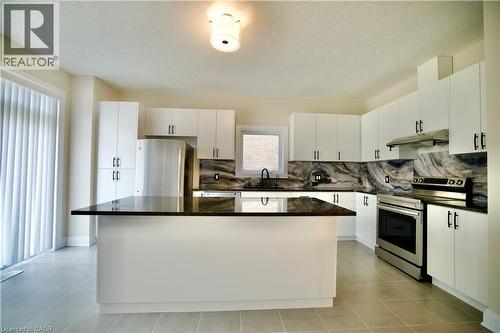 Kitchen with stainless steel appliances, a kitchen island, white cabinets, backsplash, and a textured ceiling - 559 Balsam Poplar Street, Waterloo, ON - Indoor Photo Showing Kitchen With Upgraded Kitchen