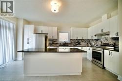 Kitchen with stainless steel appliances, a kitchen island, white cabinets, backsplash, and a textured ceiling - 