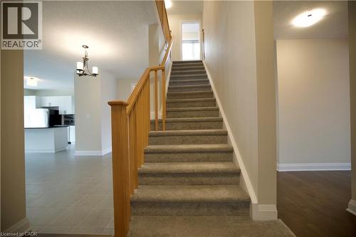 Staircase featuring hanging lights and a textured ceiling - 559 Balsam Poplar Street, Waterloo, ON - Indoor Photo Showing Other Room