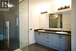 Bathroom featuring a stall shower, double vanity, and dark tile patterned floors - 