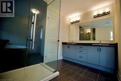 Full bathroom with a stall shower, double vanity, and dark tile patterned floors - 
