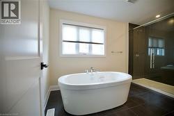 Bathroom with a soaking tub, a shower stall, and dark tile patterned flooring - 