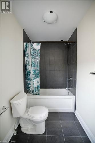 Bathroom with dark tile patterned flooring and shower / bathtub combination with curtain - 559 Balsam Poplar Street, Waterloo, ON - Indoor Photo Showing Bathroom