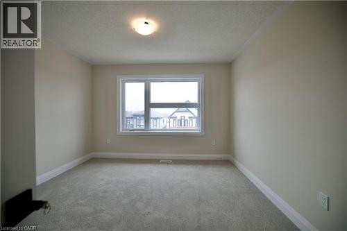 Spare room featuring a textured ceiling and light colored carpet - 559 Balsam Poplar Street, Waterloo, ON - Indoor Photo Showing Other Room