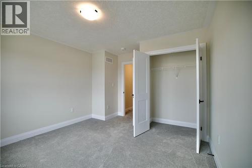 Unfurnished bedroom with light colored carpet, a textured ceiling, and a closet - 559 Balsam Poplar Street, Waterloo, ON - Indoor Photo Showing Other Room