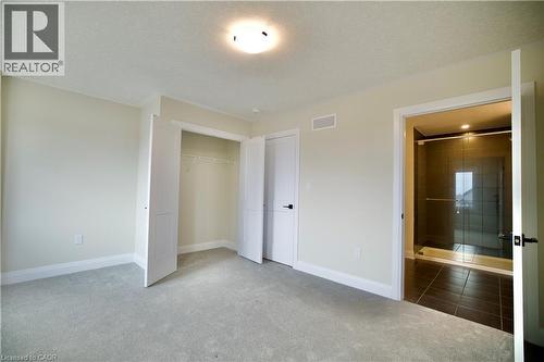 Unfurnished bedroom with carpet floors, a textured ceiling, and a closet - 559 Balsam Poplar Street, Waterloo, ON - Indoor Photo Showing Other Room