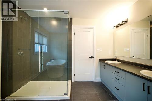 Bathroom with double vanity, a shower stall, a freestanding bath, and dark tile patterned flooring - 559 Balsam Poplar Street, Waterloo, ON - Indoor Photo Showing Bathroom