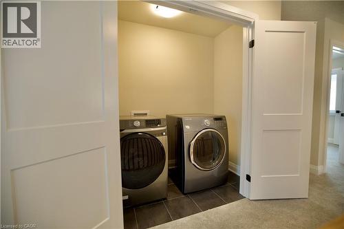 Laundry area featuring independent washer and dryer, dark tile patterned flooring, and dark colored carpet - 559 Balsam Poplar Street, Waterloo, ON - Indoor Photo Showing Laundry Room