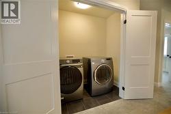 Laundry area featuring independent washer and dryer, dark tile patterned flooring, and dark colored carpet - 