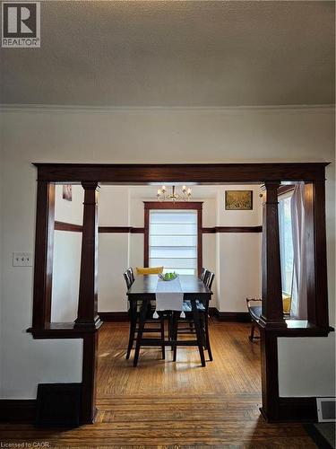 Dining room featuring dark wood finished floors, crown molding, hanging lights, and a textured ceiling - 253 Grosvenor Avenue S, Hamilton, ON - Indoor