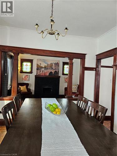 Dining room featuring a fireplace, ornamental molding, a chandelier, and decorative columns - 253 Grosvenor Avenue S, Hamilton, ON - Indoor Photo Showing Dining Room
