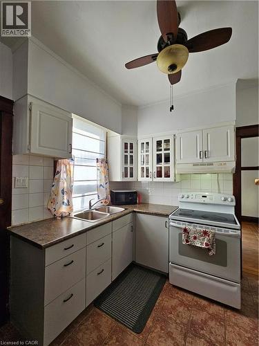Kitchen with white electric range oven, tasteful backsplash, dark countertops, ceiling fan, and crown molding - 253 Grosvenor Avenue S, Hamilton, ON - Indoor Photo Showing Kitchen With Double Sink