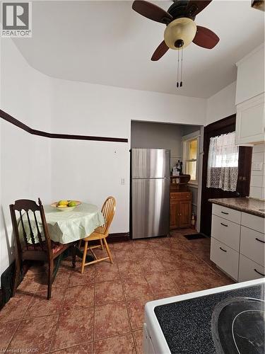 Kitchen featuring white cabinetry, white range with electric stovetop, freestanding refrigerator, dark countertops, and a ceiling fan - 253 Grosvenor Avenue S, Hamilton, ON - Indoor