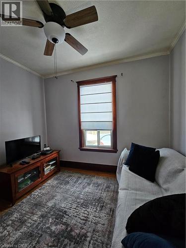 Living room with ornamental molding, a ceiling fan, wood finished floors, and a textured ceiling - 253 Grosvenor Avenue S, Hamilton, ON - Indoor