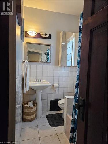 Bathroom featuring a shower with shower curtain, light tile patterned floors, and tile walls - 253 Grosvenor Avenue S, Hamilton, ON - Indoor Photo Showing Bathroom