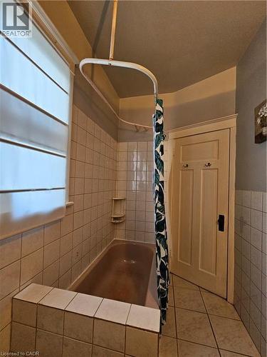 Full bathroom with shower / bath combo with shower curtain, light tile patterned floors, and tile walls - 253 Grosvenor Avenue S, Hamilton, ON - Indoor Photo Showing Bathroom