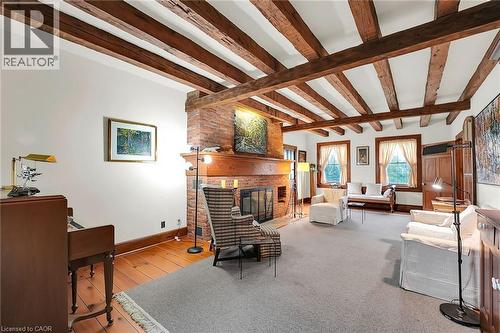Living area with a brick fireplace, light wood-type flooring, and beam ceiling - 2432 Seburn Road, Fonthill, ON - Indoor Photo Showing Other Room With Fireplace