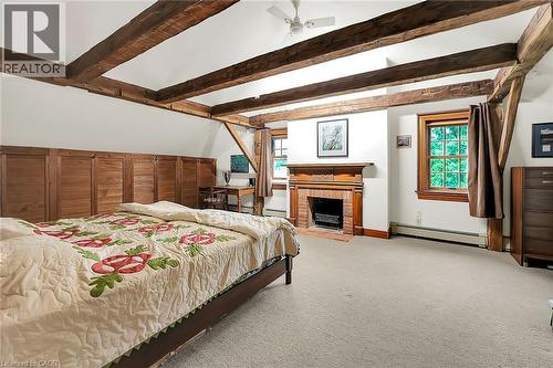Bedroom with a baseboard heating unit, a brick fireplace, light colored carpet, and beamed ceiling - 2432 Seburn Road, Fonthill, ON - Indoor Photo Showing Bedroom With Fireplace