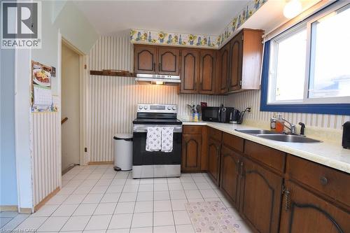 Kitchen with stainless steel electric range oven, light countertops and dark wood finish cabinets - 1345 Colonsay Drive, Burlington, ON - Indoor Photo Showing Kitchen With Double Sink