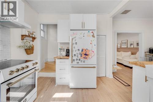 Kitchen featuring white cabinetry, white appliances, ornamental molding, light wood-style flooring, and wood counters - 6 Ben Lomond Place, Hamilton, ON - Indoor Photo Showing Kitchen