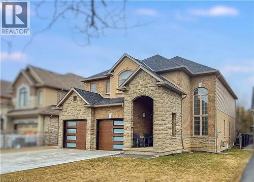 View of front of property with stone siding, a shingled roof, a front lawn, and concrete driveway - 254 Rymal Road W, Hamilton, ON - Outdoor With Facade