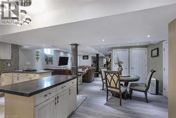 Kitchen featuring a kitchen island, open floor plan, dark countertops, tasteful backsplash, and light wood-type flooring - 