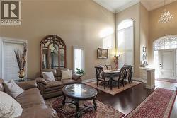 Living area with a high ceiling, ornamental molding, hardwood / wood-style floors, and suspended lighting - 