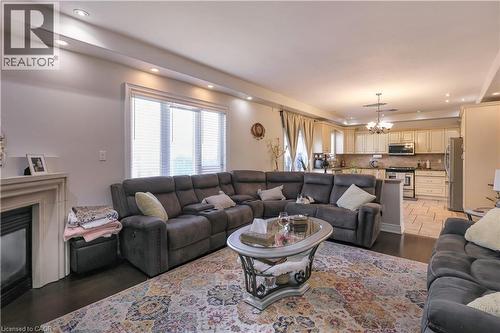 Living area featuring suspended lighting, wood finished floors, and a glass covered fireplace - 254 Rymal Road W, Hamilton, ON - Indoor Photo Showing Living Room With Fireplace