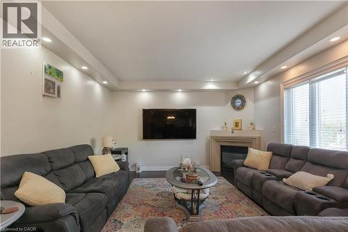 Living area featuring a raised ceiling, a glass covered fireplace, recessed lighting, and wood finished floors - 254 Rymal Road W, Hamilton, ON - Indoor Photo Showing Living Room With Fireplace