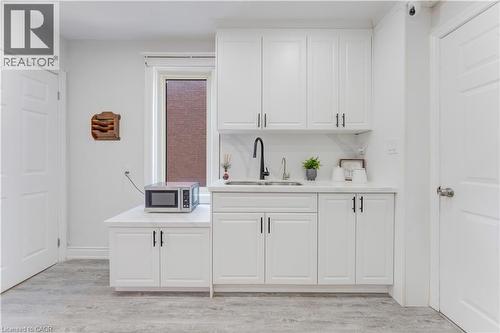Bar area featuring light wood finished floors, stainless steel microwave, white cabinets, and light stone counters - 24 Onward Avenue, Kitchener, ON - Indoor