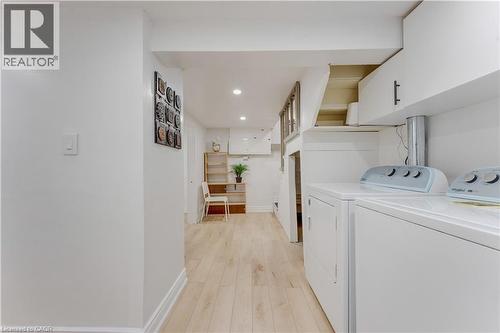 Laundry area featuring recessed lighting, light wood-style flooring, washing machine and dryer, and cabinet space - 24 Onward Avenue, Kitchener, ON - Indoor Photo Showing Laundry Room