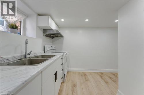 Kitchen featuring white range with electric stovetop, light countertops, light wood-style flooring, range hood, and white cabinetry - 24 Onward Avenue, Kitchener, ON - Indoor