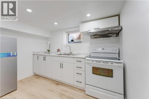 Kitchen with white electric range, light countertops, light wood-style floors, range hood, and white cabinets - 24 Onward Avenue, Kitchener, ON - Indoor Photo Showing Kitchen