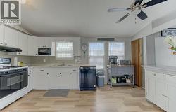 Kitchen featuring black appliances, white cabinets, light countertops, lofted ceiling, and a ceiling fan - 