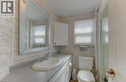 Bathroom with vanity, an enclosed shower, and tile walls - 